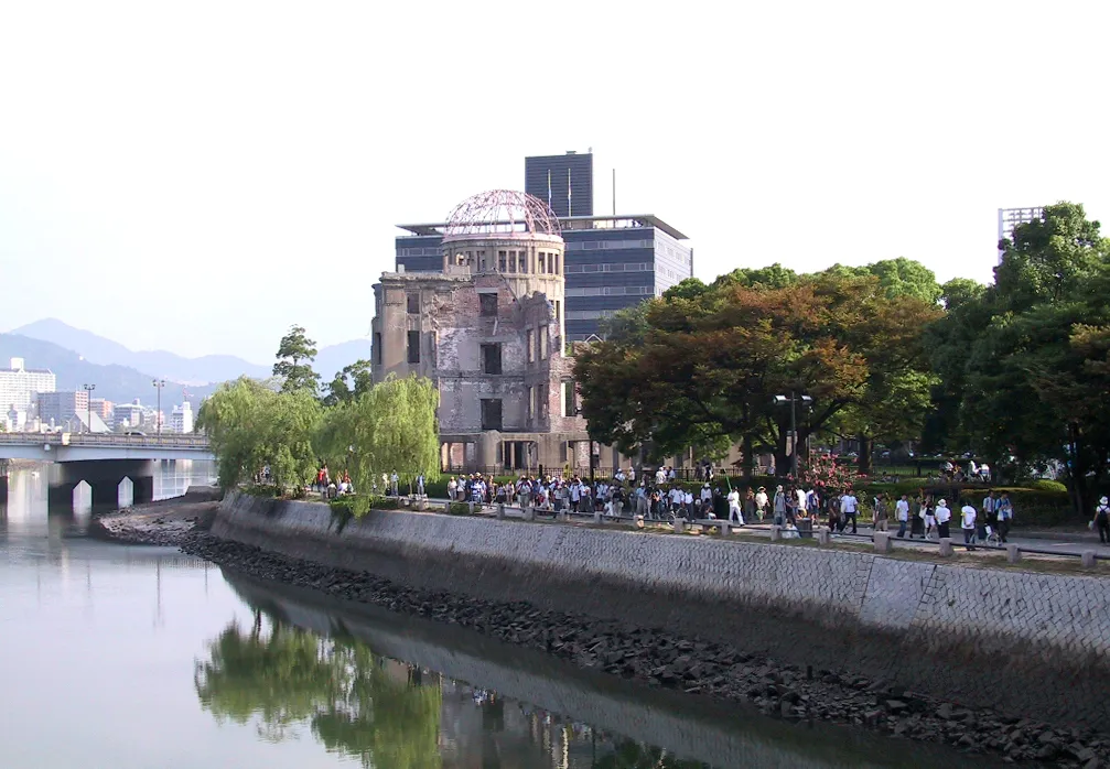 Visitors walk along the riverside path past the A-Bomb Dome in Hiroshima Peace Memorial Park on a summer evening.